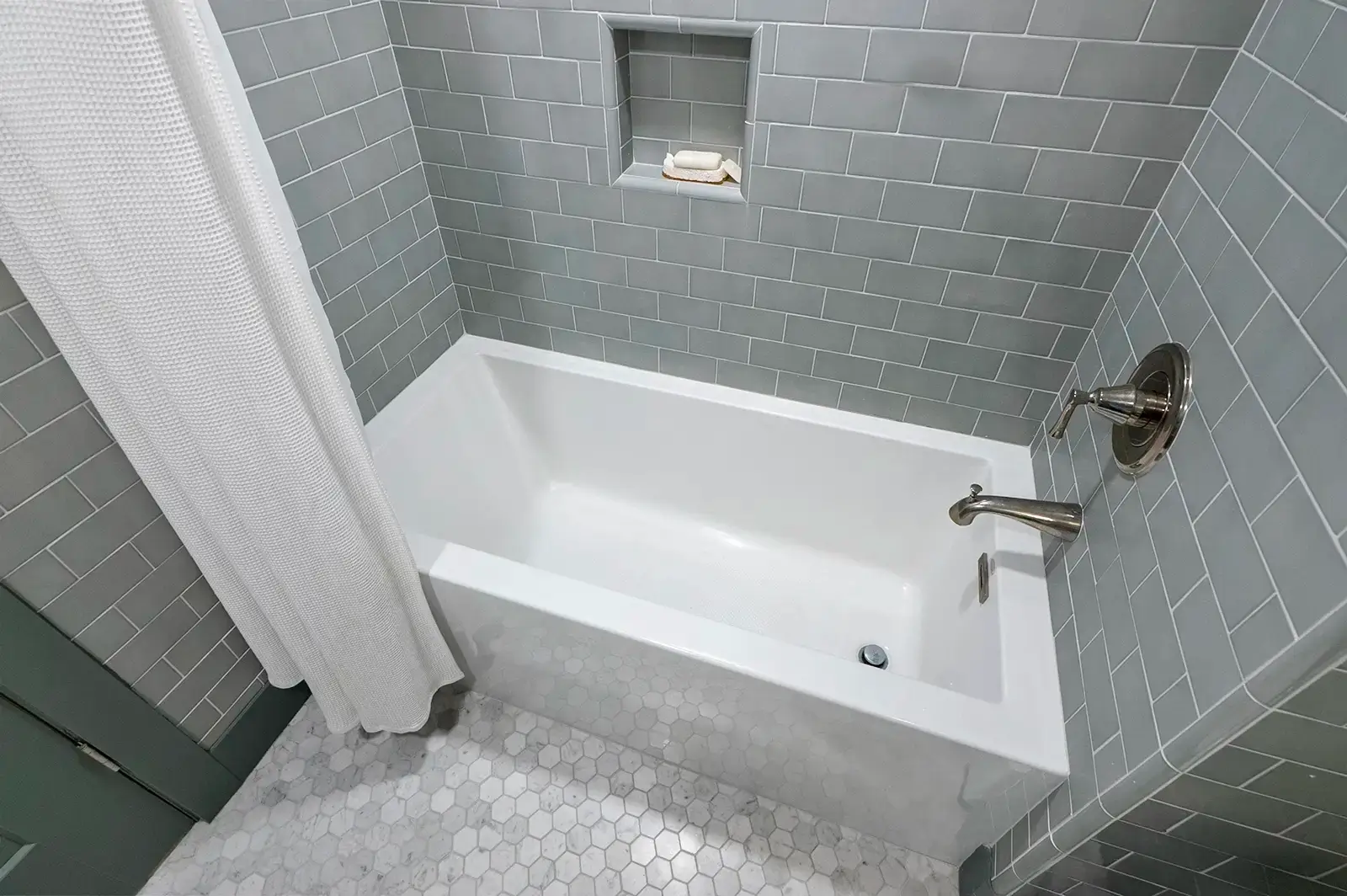 Modern bathtub surrounded by expertly installed tile work.