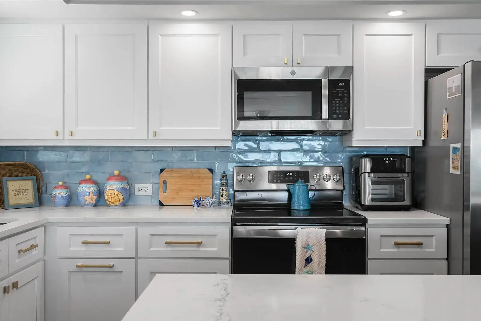 Sleek white cabinetry and stainless steel appliances highlight this kitchen from one of our condo renovations in Ponce Inlet.